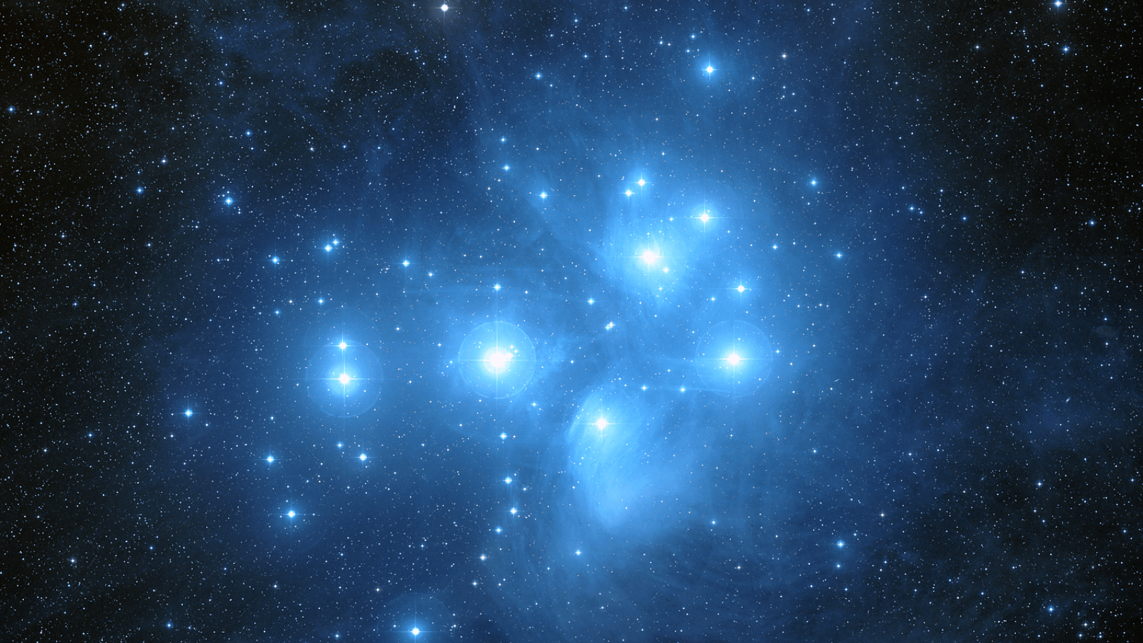 Wide-field image of the Pleiades star cluster (Messier 45) showing bright blue stars wreathed in reflection nebulosity